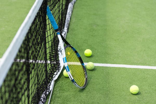 Tennis balls and racket on a green tennis hard court. High quality photo